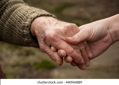 Old and young person holding hands. Elderly care and respect