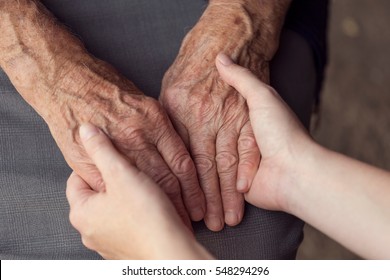 Old and young person holding hands. Elderly care and respect, selective focus