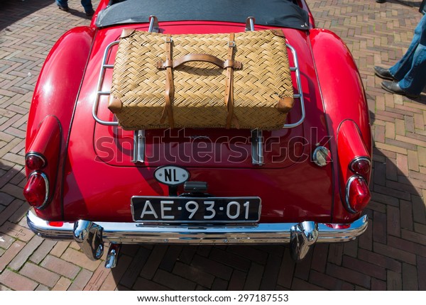 OLDENZAAL, NETHERLANDS - APRIL 27, 2015: Red\
oldtimer car with suitcase during the 14th orange tour. This annual\
tour takes places during the king\'s birthday celebrations, a\
national holiday.