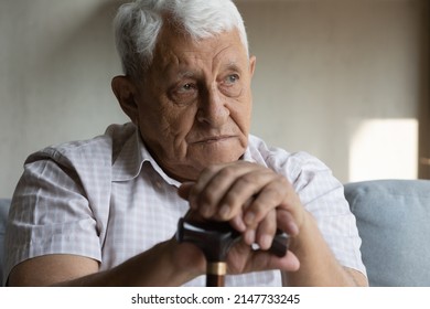 Older 70s man resting on couch staring aside looks upset hold cane stick due walking balance, recollects memories feels lonely. Ageing, elderly generation citizen health-care concept - Powered by Shutterstock