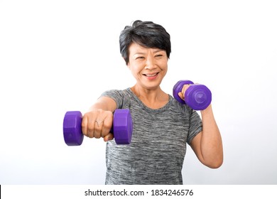 An Older Active Senior Asian Woman Training, Exercising, Workout At Home With Lifting Weight Dumbbells Isolated On White Background. Exercise Active And Healthy For Older, Elder, And Senior Concept.