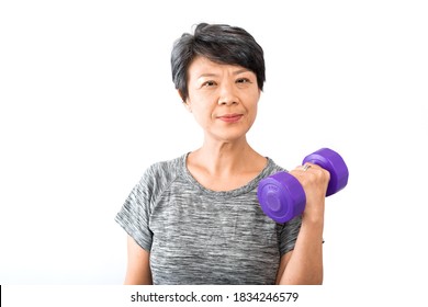 An Older Active Senior Asian Woman Training, Exercising, Workout At Home With Lifting Weight Dumbbell Isolated On White Background. Exercise Active And Healthy For Older, Elder, And Senior Concept.