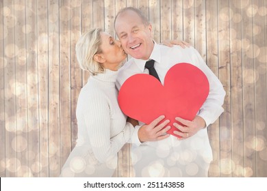 Older Affectionate Couple Holding Red Heart Shape Against Light Glowing Dots Design Pattern