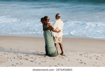 An older African American couple stands affectionately on the beach, laughing and embodying love and companionship in a tranquil coastal setting. - Powered by Shutterstock