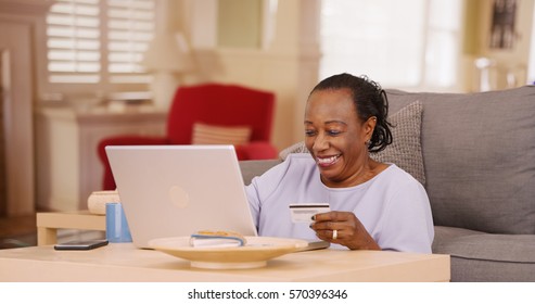 An Older African American Woman Uses Her Credit Card And Laptop To Do Some Online Shopping