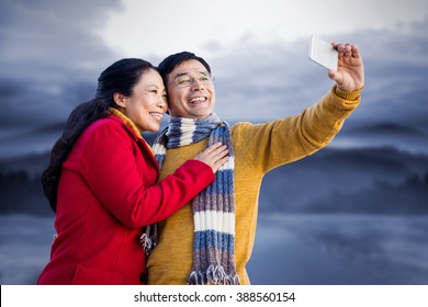 Older Asian Couple On Balcony Taking Selfie Against Road Leading Out To The Horizon At Night