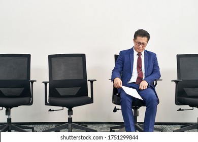 Older Asian Job Seeker Sitting In Chair Appears To Be Frustrated And Defeated