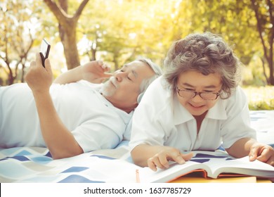 Older Asian People, Senior Couple, Elderly Man And Elderly Woman Get Enjoying In Park. Old Husband Listening Music, Lay Down On Old Wife Back. Grandma Reading Book, Smile Face Senior Couple Happiness 