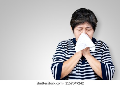 Older Asian Woman Is Having Flu And Sneezing From Sickness Seasonal Virus Problem With Isolated Background. Fever And Cold In Senior People With Influenza Illness And Health Insurance Concept.