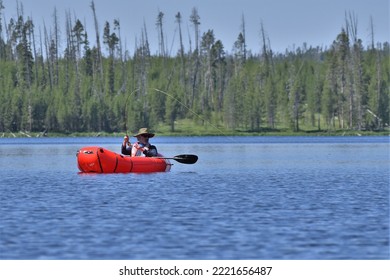 Older, Bearded Caucasian Man Fishing From A Red Inflatable Kayak.  Rod Bent With Fish On.