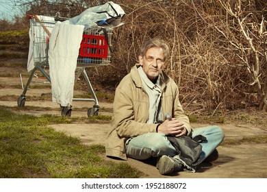 Older beggar man with his property in shopping cart