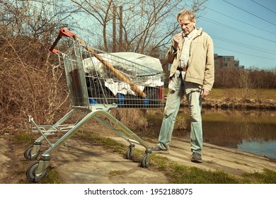 Older Beggar Man With His Property In Shopping Cart