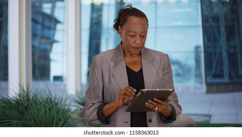 Older Black Businesswoman Uses Digital Tablet Outside Office Building