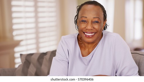 An older black woman happily looks at the camera