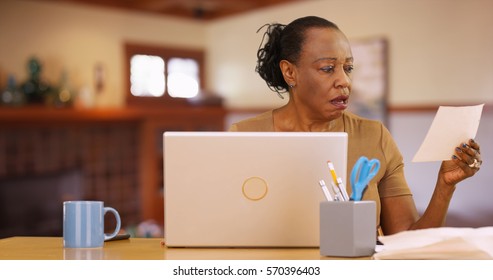 An Older Black Woman Sitting In Front Of Computer Shocked By Bill Payments