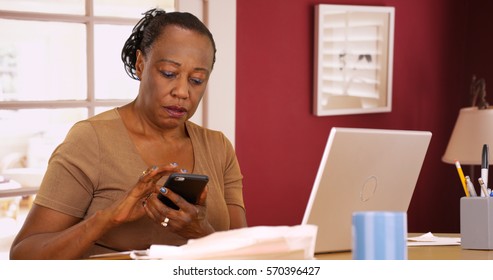 An older black woman uses her phone and laptop to do her taxes