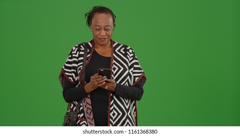 An Older Black Woman Using Mobile Phone To Text On Green Screen