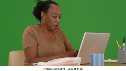 An Older Black Woman Working On Her Laptop Sitting At Desk On Green Screen