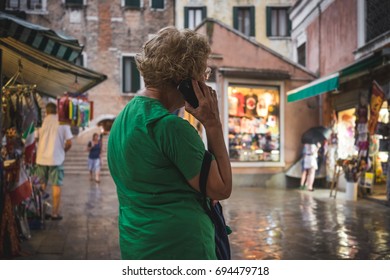 Older Blonde Lady Talking On The Phone, Streets During Storm.