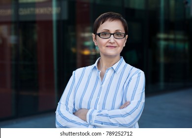 Older business woman headshot. Close-up portrait of executive, teacher, principal, CEO. Confident and successful middle aged woman 40 50 years old wearing glasses and shirt.