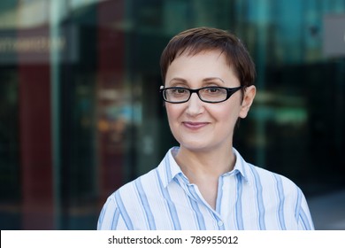 Older Business Woman Headshot. Close-up Portrait Of Executive, Teacher, Principal, CEO. Confident And Successful Middle Aged Woman 40 50 Years Old Wearing Glasses And Shirt And Smiling