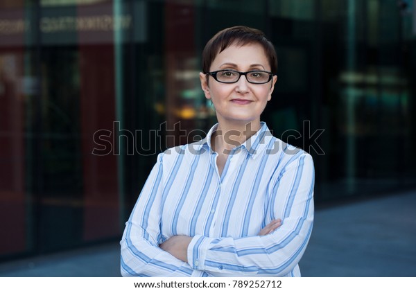 Older business woman\
headshot. Close-up portrait of executive, teacher, principal, CEO.\
Confident and successful middle aged woman 40 50 years old wearing\
glasses and shirt.