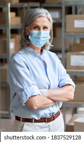 Older Business Woman Retail Seller, Entrepreneur, Small Business Owner Wearing Face Mask And Gloves For Covid 19 Protection Looking At Camera Standing In Delivery Storage Warehouse, Vertical Portrait.