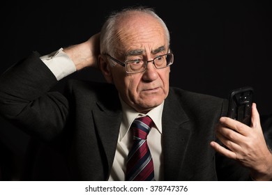 Older Businessman, Wearing Eyeglasses On Black Background, Uses Smart Phone, Has Video Chat