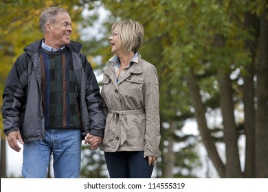 Older Casual Couple Walking In The Park Outdoors