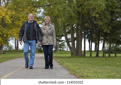 Older Casual Couple Walking In The Park Outdoors