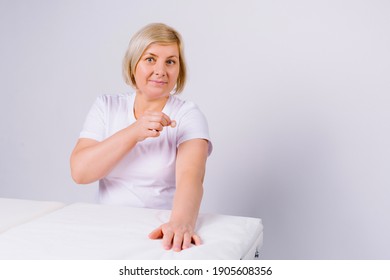 An Older Caucasian Woman Looks At The Camera And Shows The Local Reaction On Her Arm After The Vaccine. White Background And Empty Side Space.