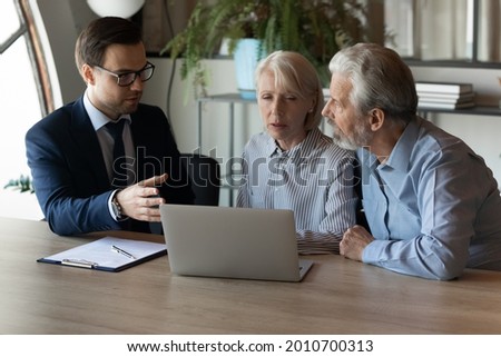 Older clients consulting agent, broker about house selling, medical insurance terms, trust fund investment, meeting at laptop in office. Senior couple discussing wills with lawyer, solicitor, notary
