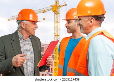 Older Construction Supervisor With Younger Worker Helper Construction Site. Managers Wearing Protective Workwear, Hard Hat, Construction Cranes On Skyline. Construction Workforce, Working Labor Man.