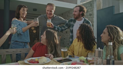 Older Couple Arriving At Backyard Barbecue Garden Party. Group Of Friends Welcoming Parents Celebrating Life With Food And Leisure. Happy People Toasting With Glasses