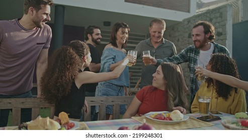 Older Couple Arriving At Backyard Barbecue Garden Party. Group Of Friends Welcoming Parents Celebrating Life With Food And Leisure. Happy People Toasting With Glasses