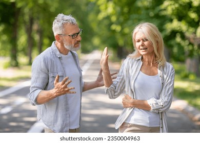 Older Couple Conflicts. Mature Spouses Arguing While Walking In Park, Angry Senior Man And Woman Quarreling Outdoors, Suffering Misunderstanding And Marital Crisis, Wife Making Stop Gesture With Hand - Powered by Shutterstock