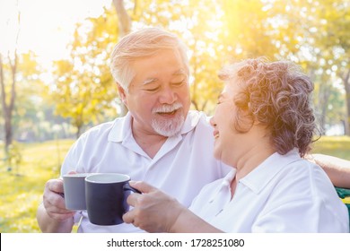 Older Couple Drinking Delicious Hot Coffee Or Tea At Park With Happiness. Senior Man And Elderly Woman Hold Cup Of Coffee And Say Cheers Together For Good Health. Retirement Couple Laughing Together