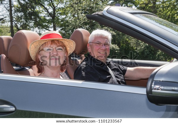 older couple\
drives with a luxury convertible\
car