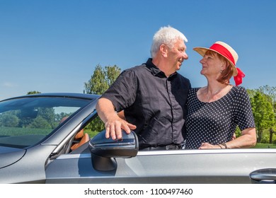 Older Couple Driving Convertible Car Enjoying A Summer Day