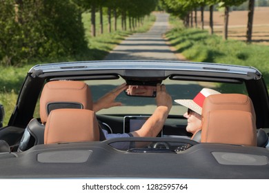 Older Couple Driving Convertible Car Enjoying A Summer Day