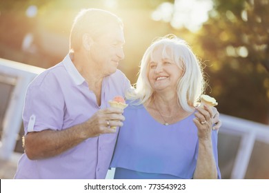 Older Couple Eating Ice Cream And Walking In The Sunlight. Old Marriage. Love Concept