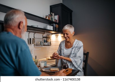 Older Couple Eating And Smiling In Pajamas