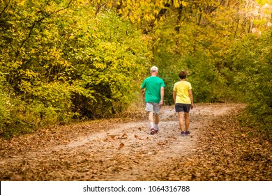 Older Couple Energetically Walking On The Trail In A Park In The Fall