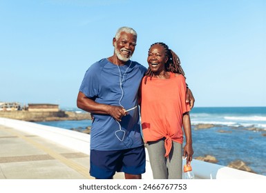 An older couple enjoys a joyful walk along the seaside promenade, smiling and embracing the sunny day. - Powered by Shutterstock