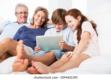 Older Couple And Grandchildren Using Digital Tablet