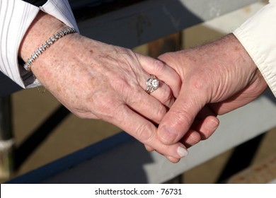 An Older Couple Holds Hands Showing A Wedding Ring A Brcelet And That Love Is In The Air