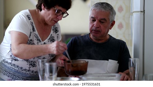 Older Couple At Home Eating Lunch, Wife Serving Food To Husband, Authentic And Candid