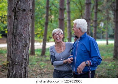 Older couple jogging in the park with distance tracker watch on hands  and smile  - Powered by Shutterstock