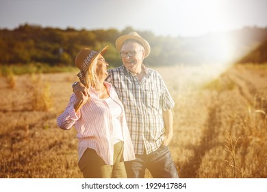 Older couple joying in retirement.They standing on meadow andjoying in sunset.	
