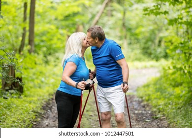 Older Couple Kissing In The Woods While Trekking. Summer Outdoor Activities.